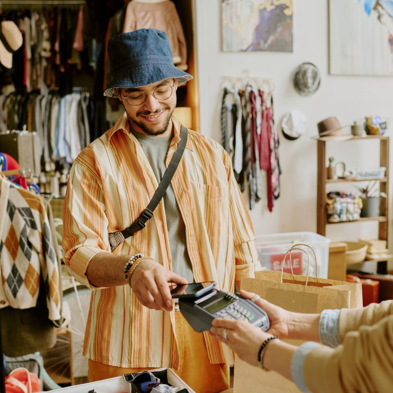 A young man in a stylish outfit paying for some new clothes at a local Livonia store.