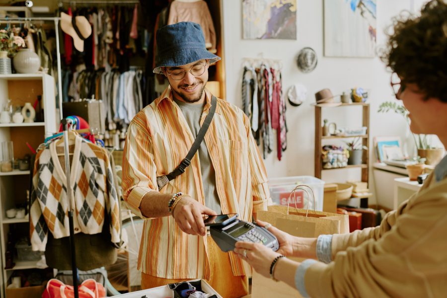A young man in a stylish outfit paying for some new clothes at a local Livonia store.