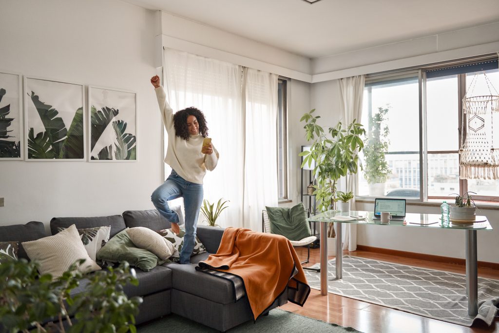 A woman dancing in her apartment decorated with damage-free decor.