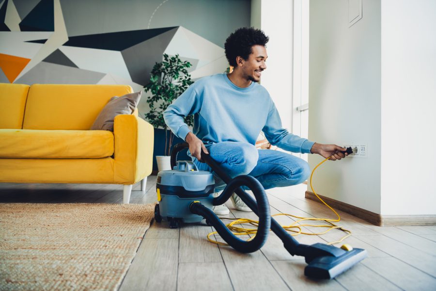 A man plugs in his vacuum and uses apartment cleaning tips to get his apartment sparkling for the new year.