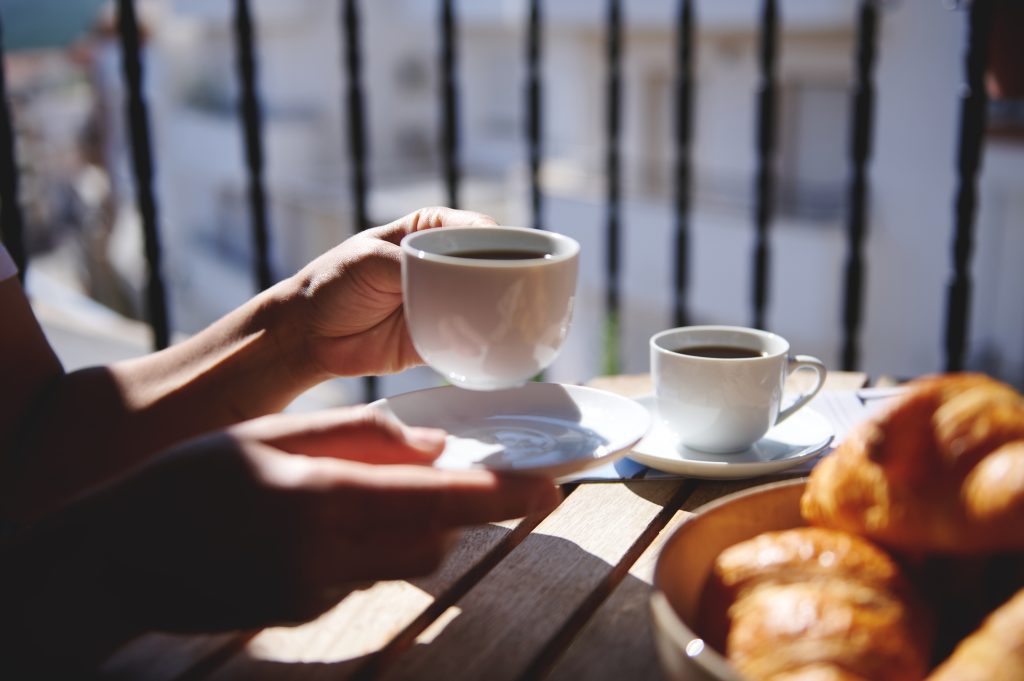 Small bistro table with coffee and breakfast on a Livonia apartment balcony.